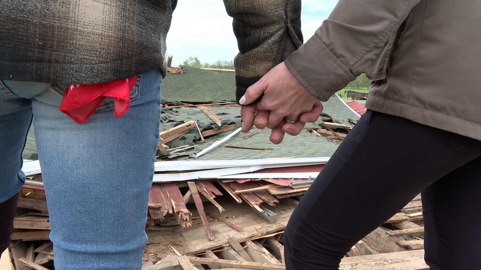 Adam & Haley Auvenshine hold hands as they observe their barn destroyed by a tornado